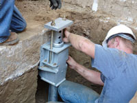 Foundation repair contractors installing the foundation bracket in Troy.