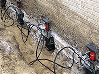 Using foundation push piers to lift a foundation during a repair in Queensbury.