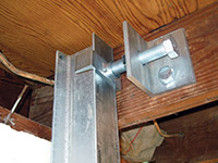 Securing the i-beam system to the top of the floor joist in a foundation wall repair in Latham.
