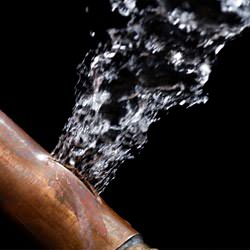 A bursting copper pipe in Saratoga Springs, with water gushing out.