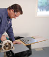 installing a waterproof vapor barrier on a basement floor to prepare for basement carpeting in a Saratoga Springs home